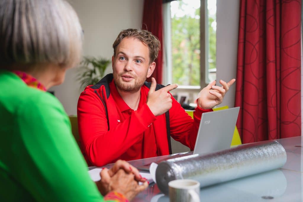 Energiecoach praat met oudere dame aan tafel