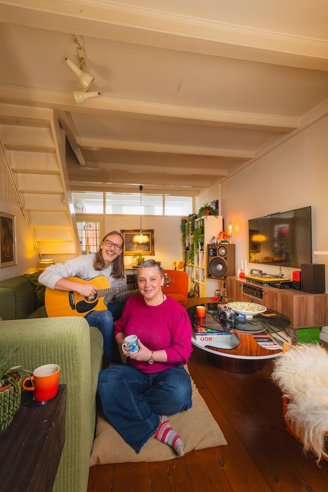 man en vrouw zitten met gitaar in de woonkamer